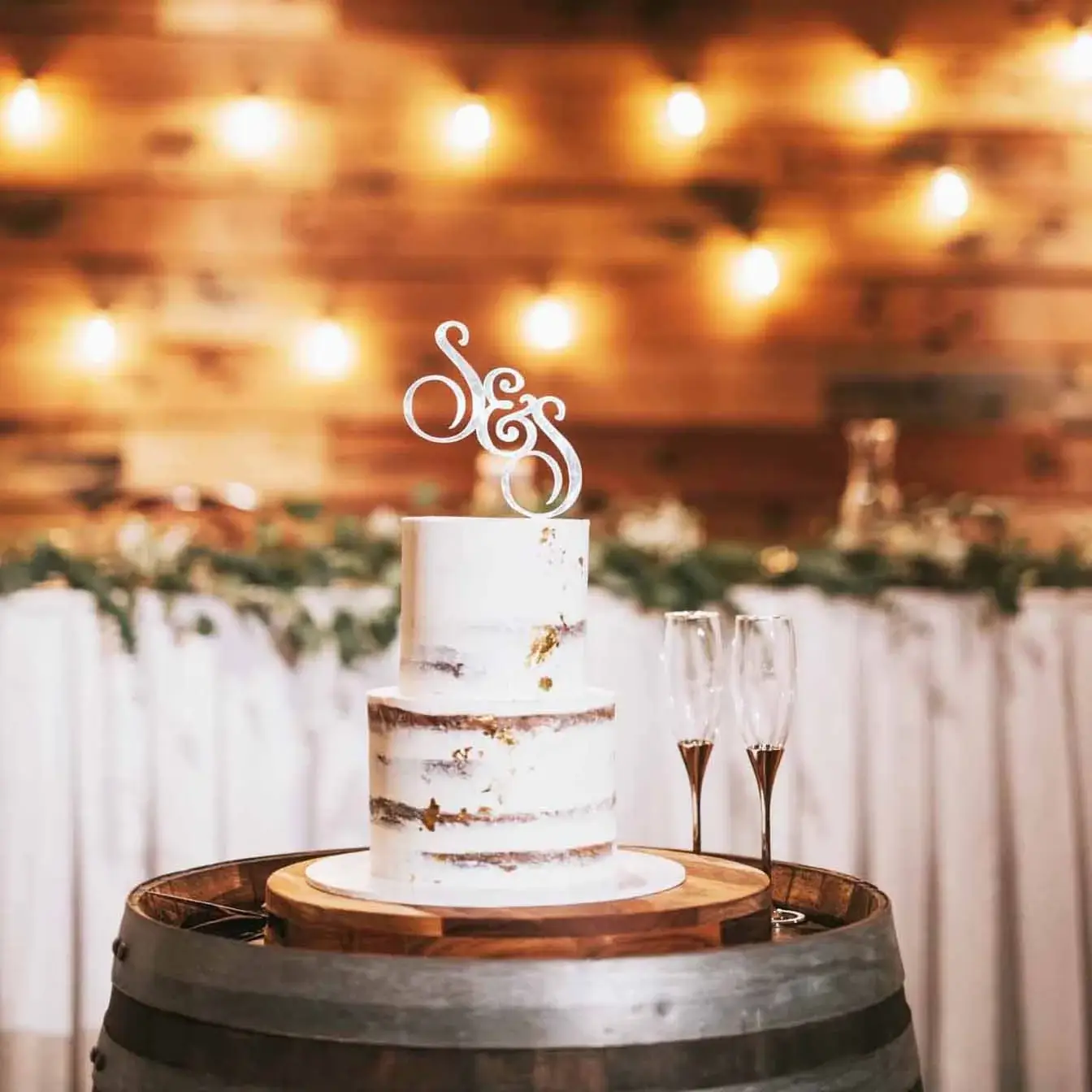 Golden Romance Semi-Naked Wedding Cake - A two-tier cake with a semi-naked finish, customized cake topper, and scattered gold leafing, a captivating blend of simplicity and sophistication for your special day.